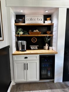 a coffee bar with white cabinets and black appliances