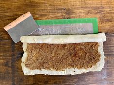 a piece of bread on a wooden table with a knife and sharpener next to it