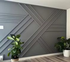 two potted plants are sitting in front of a wall with geometric designs on it