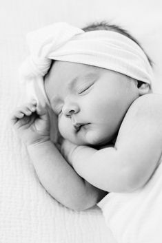 a black and white photo of a sleeping baby with a headband on it's head