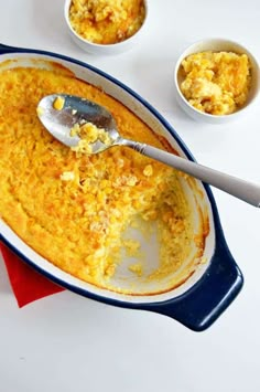 a casserole dish with a spoon in it and two bowls on the side