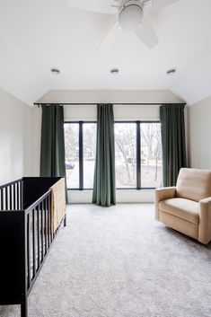 an empty room with a baby crib and green curtains on the window sill