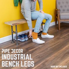 a man sitting on top of a wooden bench in front of a wall with yellow walls