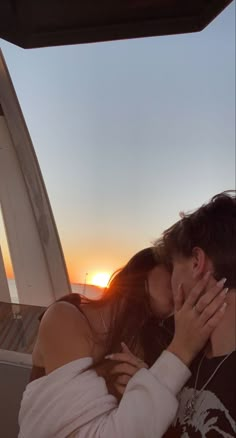 a man and woman kissing in the back of a car at sunset or sunrise on a boat