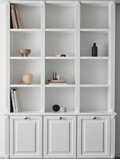 a white bookcase filled with lots of books and vases on top of it