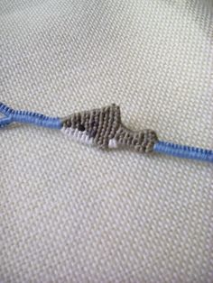 a close up of a blue cord with a small bead in the shape of a bird