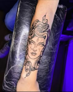 a woman's arm with a tattoo on it and a snake wrapped around her wrist