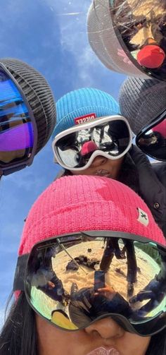 several people wearing ski goggles and hats are looking up at the sky with their reflection in them