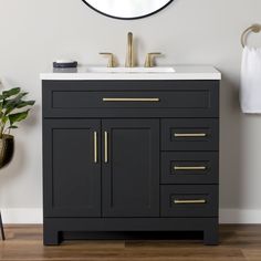 a bathroom vanity with a mirror above it and a plant on the floor next to it