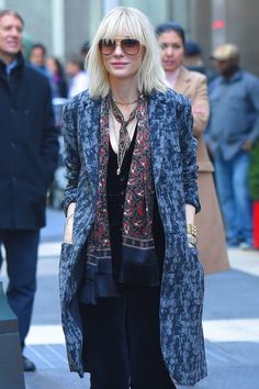 a woman with blonde hair and sunglasses is walking down the street