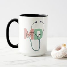 a black and white coffee mug next to a donut