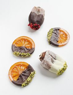 four desserts are arranged in the shape of an orange slice and chocolate covered pastry