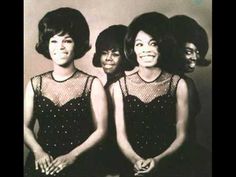 three women in black dresses with pink dots on their body and one woman sitting down