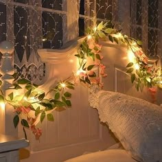 a white bed topped with lots of lights next to a window