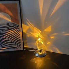 a lamp that is on top of a table next to a picture and an art piece