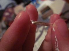 a person is holding a small piece of silver wire in their hand with white writing on it