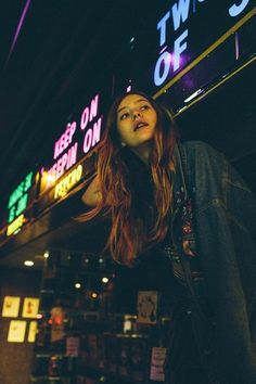 a woman standing in front of a neon sign