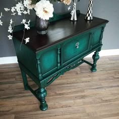 a vase with flowers sitting on top of a green dresser