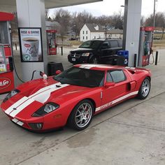 a red sports car parked in front of a gas station