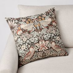 a pillow on a couch with an ornate design in the middle and two birds sitting on it