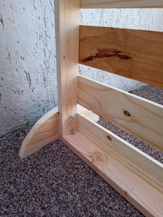 a wooden bed frame sitting on top of carpeted floor next to a white wall