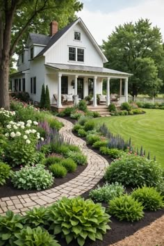 a white house sitting on top of a lush green hillside next to a garden filled with flowers