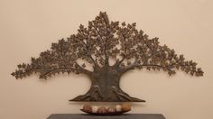 a metal tree sculpture sitting on top of a table next to a bowl of shells