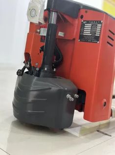 a red and black machine sitting on top of a tile floor next to a white wall