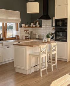 a kitchen with white cabinets and wooden floors