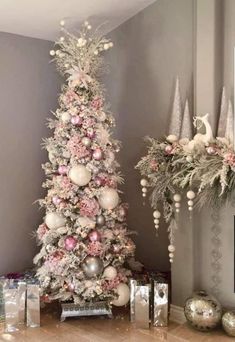 a white christmas tree with pink and silver ornaments in the corner next to other decorations