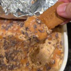 a person holding a piece of food in front of some foil on a plate with other items