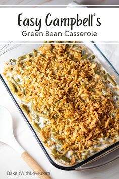 green bean casserole in a glass dish on a white table with spoons