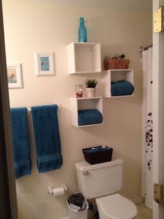 a white toilet sitting in a bathroom next to a shower and towels on the wall