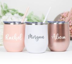 three personalized tumblers with straws in them sitting on a table next to flowers