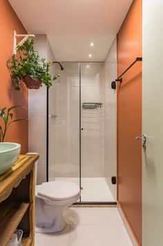 a white toilet sitting next to a walk in shower under a bathroom mirror above a sink