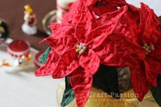 red poinsettia flowers in a glass vase on a table with other decorations