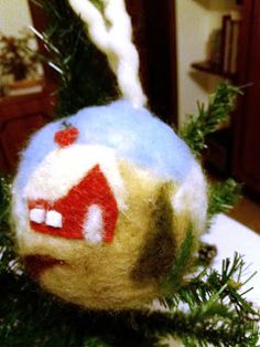 an ornament hanging from a christmas tree in the shape of a ball with a house on it