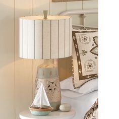 a lamp that is on top of a night stand next to a bed with pillows