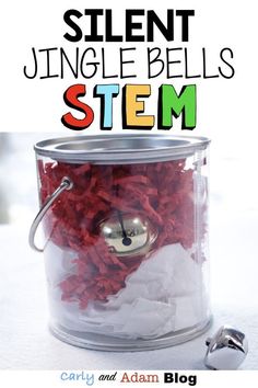 a jar filled with red shredded paper sitting on top of a white table next to a bell