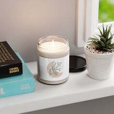 a candle sitting on top of a table next to a book and a potted plant