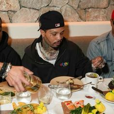 two men sitting at a table with plates of food and drinks in front of them