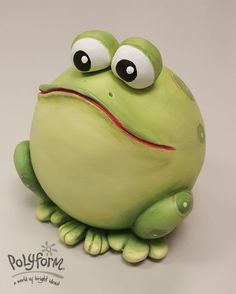 a cake shaped like a frog with big eyes and one eye wide open, sitting on a white surface