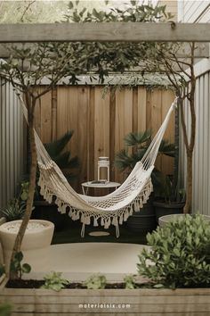 Cozy hammock in a small, tranquil garden surrounded by plants and a wooden fence.