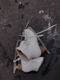 two pairs of white ice skates sitting next to each other on the ground,