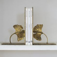 two books are sitting on a shelf next to each other, one has a leaf shaped bookend