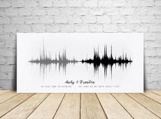 a black and white sound wave art print on a wooden table next to a brick wall