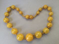 "Lovely egg yolk Bakelite single strand necklace. Hand tied graduated beads. Romantic, yellow necklace. Hidden bead clasp. Simply beautiful, gleaming, set of beads. Large knot, hand tied 1930s style. Chunky! Graduated beads: 8mm (smallest) to 17mm (largest) 15 1/2\" necklace Attention: All items are listed to the best of our observation, but they are pre-owned and pre-loved (meaning we may have missed something minor and/or be in need of light cleaning.) Please read our shop policies and/or conv Classic Yellow Round Bead Jewelry, Vintage Yellow Single Strand Jewelry, Yellow Costume Jewelry Necklace For Formal Occasions, Yellow Costume Jewelry Necklace For Formal Events, Formal Yellow Jewelry With Round Beads, Vintage Polished Yellow Beads Jewelry, Yellow Single Strand Beads For Jewelry Making, Vintage Yellow Round Bead Necklaces, Vintage Yellow Jewelry With Polished Beads