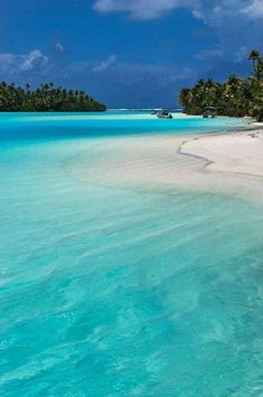 the water is crystal blue and clear with white sand on it, surrounded by palm trees