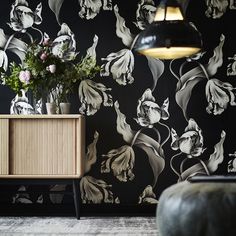 a black and white floral wallpaper in a living room with a plant on the sideboard