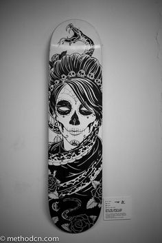 a skateboard with a skull painted on it's face and chain around its neck